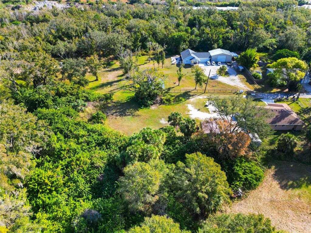 An aerial view shows a residential property with two houses, outbuildings, and surrounding wooded areas — 7564 19TH STREET E, SARASOTA, FL