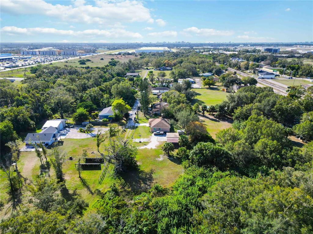 An aerial view shows a residential property with multiple buildings, trees, and a gravel driveway — 7564 19TH STREET E, SARASOTA, FL