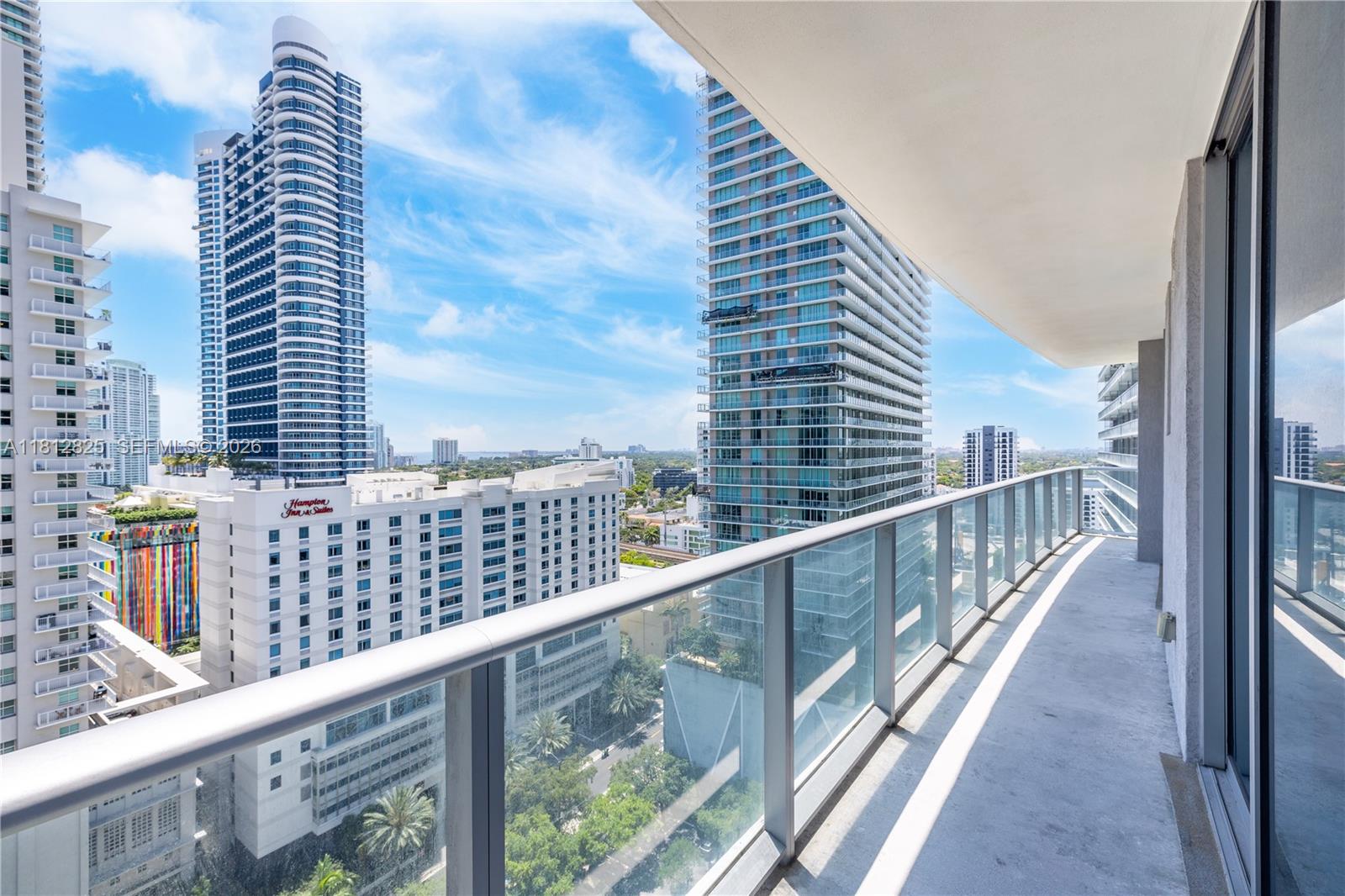 A high-rise balcony with a glass railing overlooks a city skyline with multiple tall buildings — 1100 S Miami Ave # 1704, Miami FL 33130, MIAMI, FL