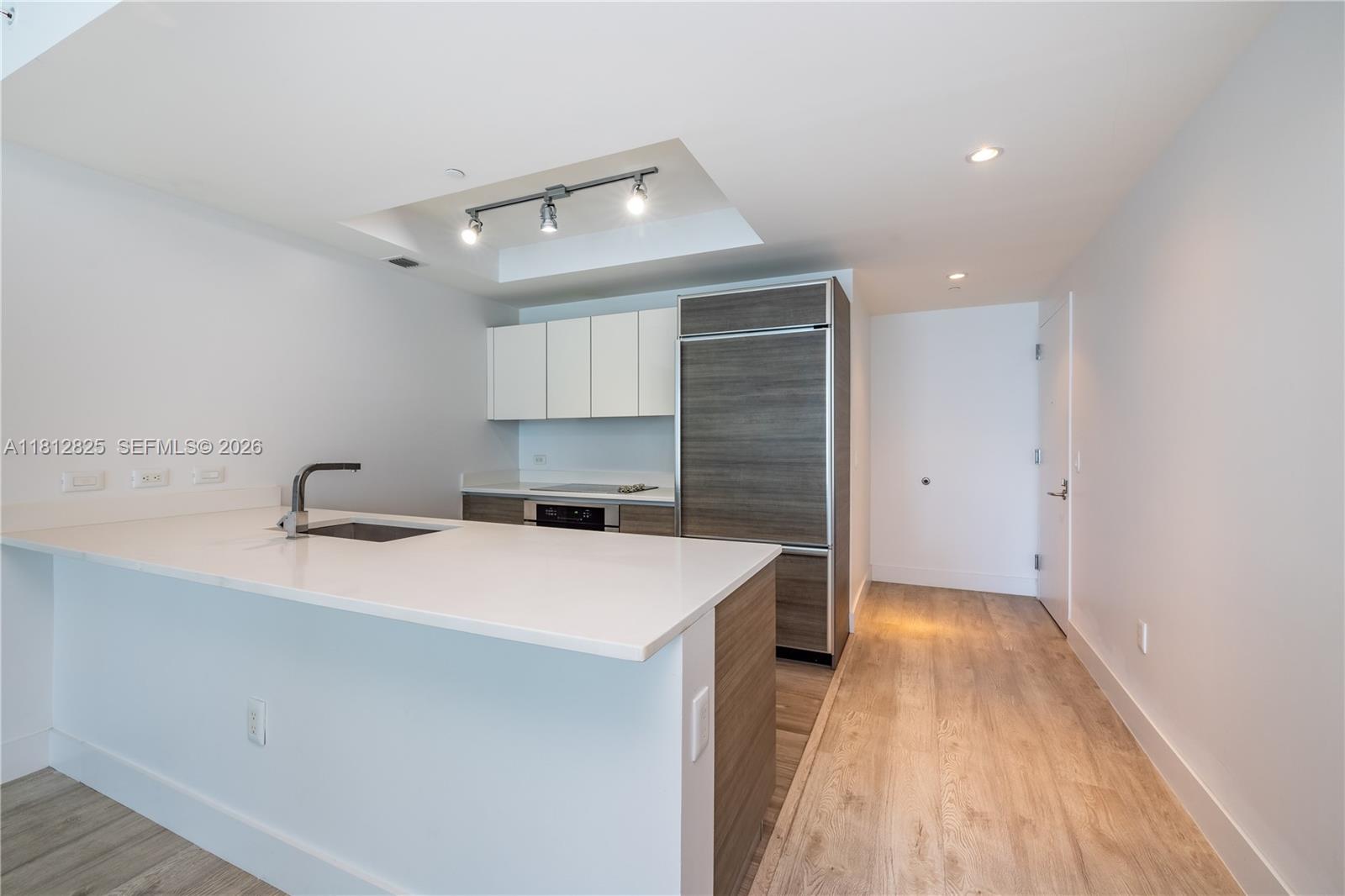 A modern kitchen features white countertops, wood-toned cabinetry, and a stainless steel refrigerator — 1100 S Miami Ave # 1704, Miami FL 33130, MIAMI, FL