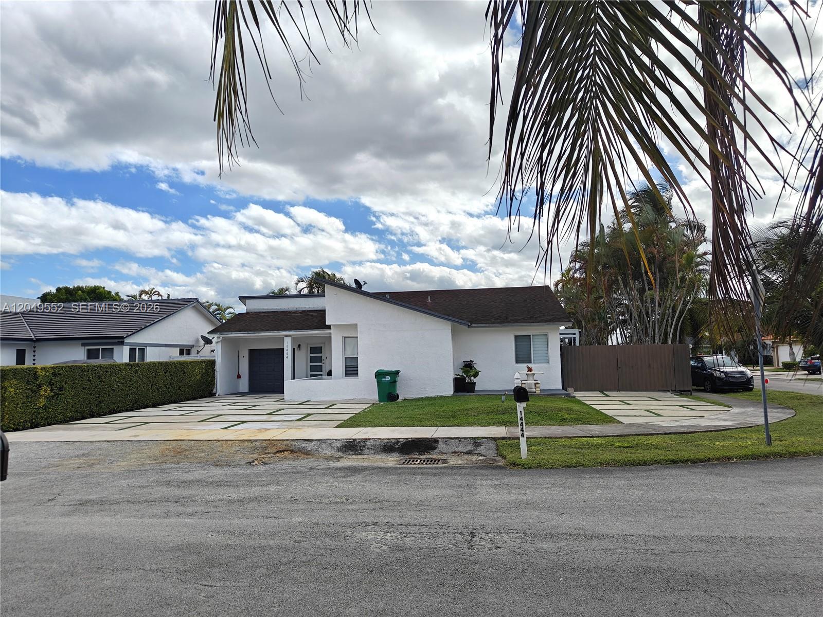 A white single-story house features a paved driveway, a small lawn, and a dark roof — 14444 SW 107th Ter, Miami FL 33186, MIAMI, FL