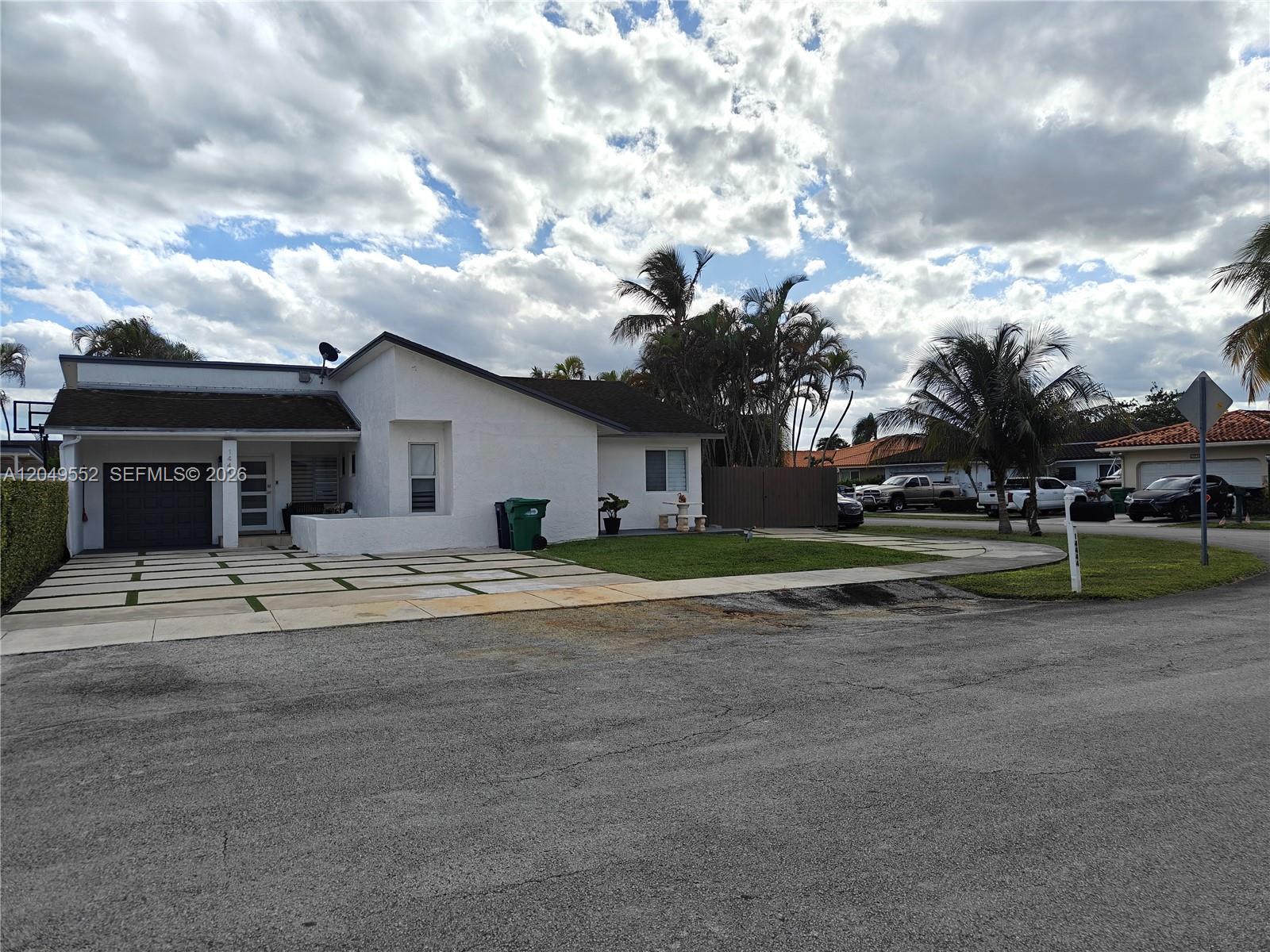A white single-story house features a paved driveway, a garage, and palm trees — 14444 SW 107th Ter, Miami FL 33186, MIAMI, FL