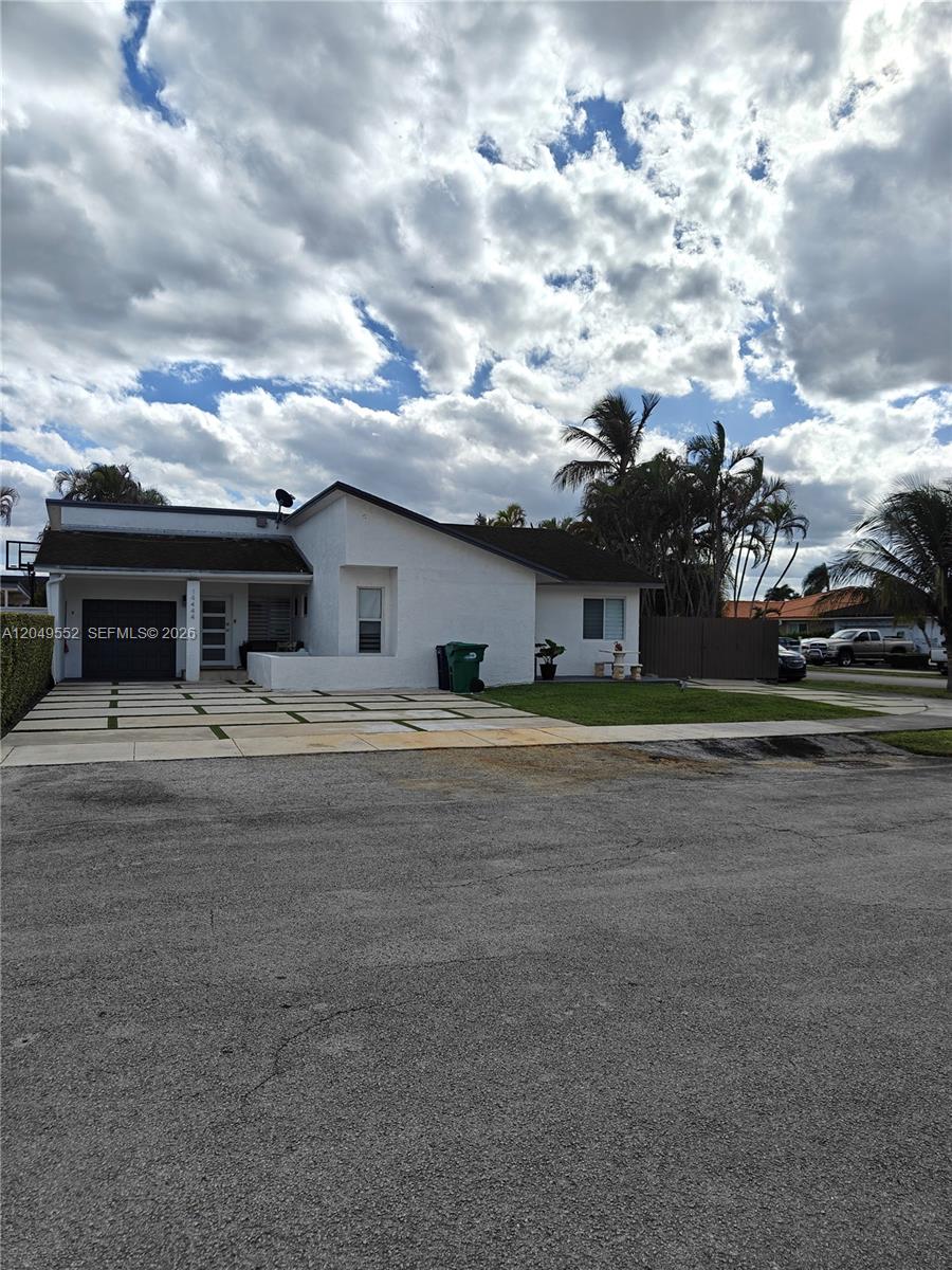 A white, single-story house features a dark garage door and a paved driveway with grass — 14444 SW 107th Ter, Miami FL 33186, MIAMI, FL