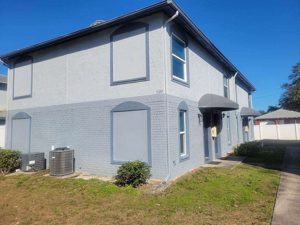 A two-story building with gray painted brick and stucco siding features boarded-up windows — 5122 TEMPLE HEIGHTS ROAD UNIT D, TAMPA, FL