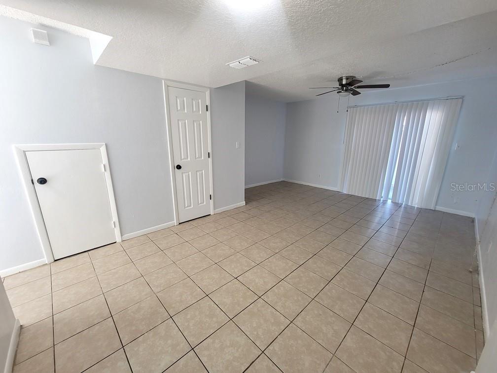 An empty room features light-colored tile flooring, a ceiling fan, and a sliding glass door — 5122 TEMPLE HEIGHTS ROAD UNIT D, TAMPA, FL
