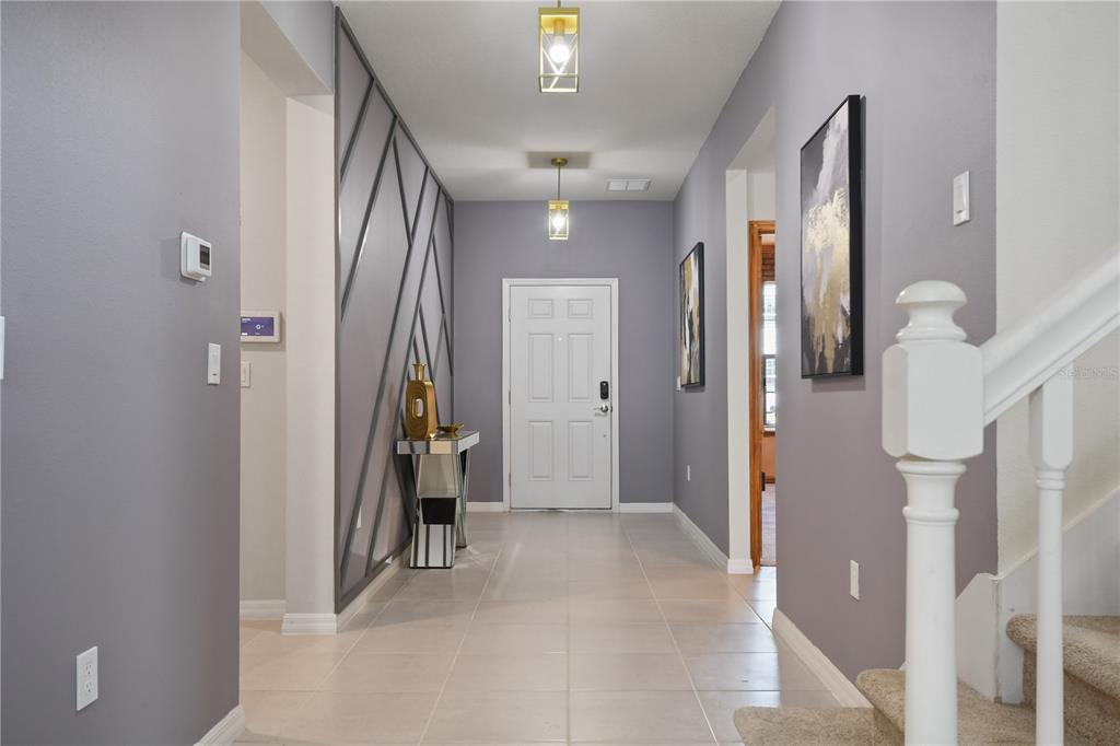 A foyer with gray walls, a geometric accent wall, tile flooring, and a white door — 4157 LANA AVENUE, DAVENPORT, FL