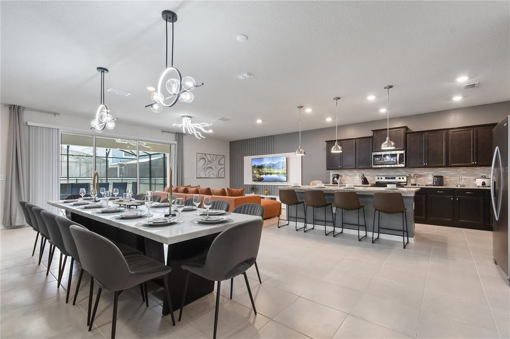 An open-concept kitchen, dining area, and living room featuring dark cabinetry and tile flooring — 4157 LANA AVENUE, DAVENPORT, FL