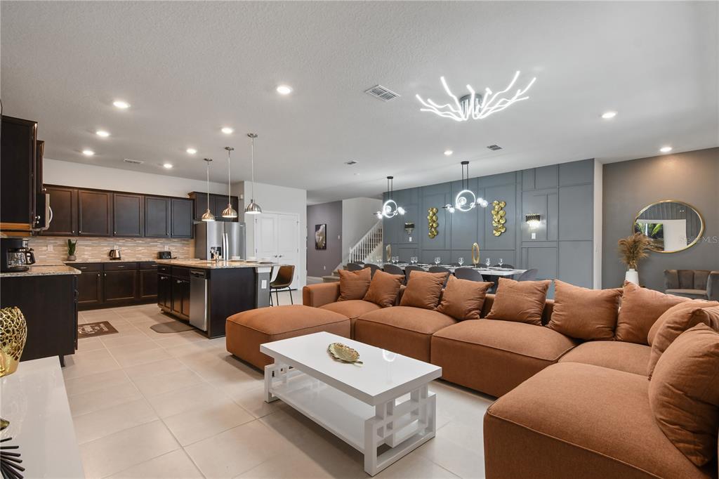 An open-concept living room and kitchen featuring dark cabinetry, a large brown sectional, and dining area — 4157 LANA AVENUE, DAVENPORT, FL