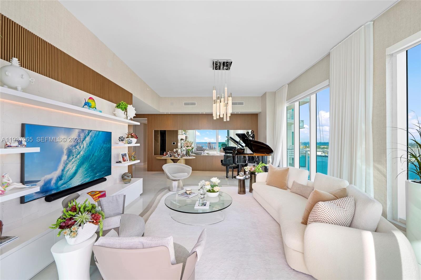 A modern living room features a grand piano, a large television, and floor-to-ceiling windows — 900 Brickell Key Blvd # 2004, Miami FL 33131, MIAMI, FL
