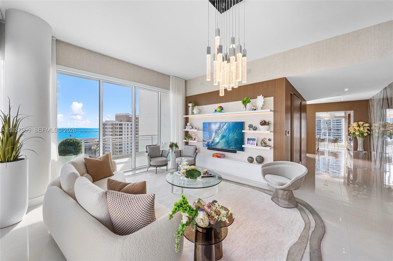 A modern living room features a large sectional sofa, a glass coffee table, and ocean views — 900 Brickell Key Blvd # 2004, Miami FL 33131, MIAMI, FL
