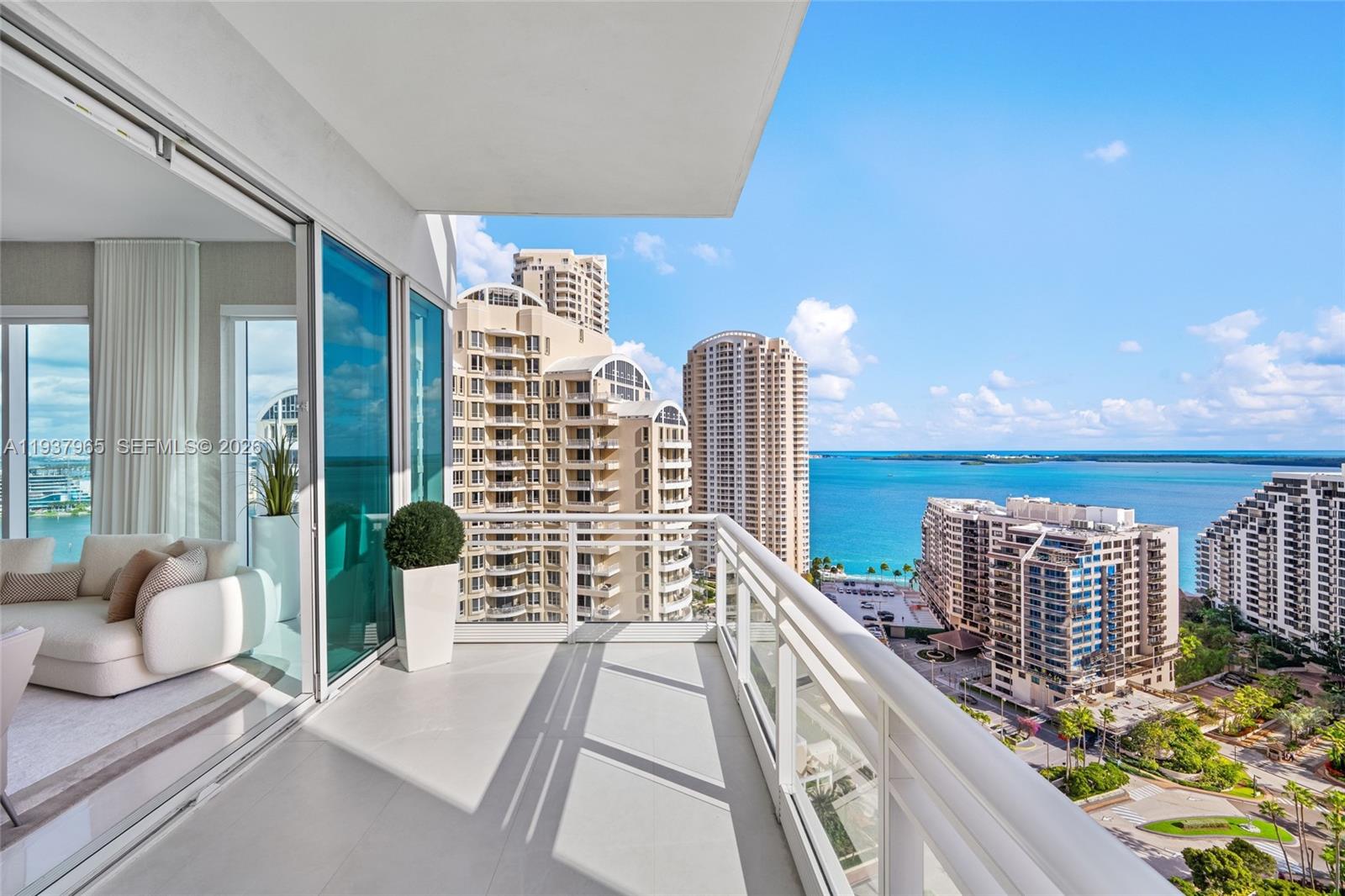 A balcony with glass railings overlooks a coastal city skyline and the ocean — 900 Brickell Key Blvd # 2004, Miami FL 33131, MIAMI, FL