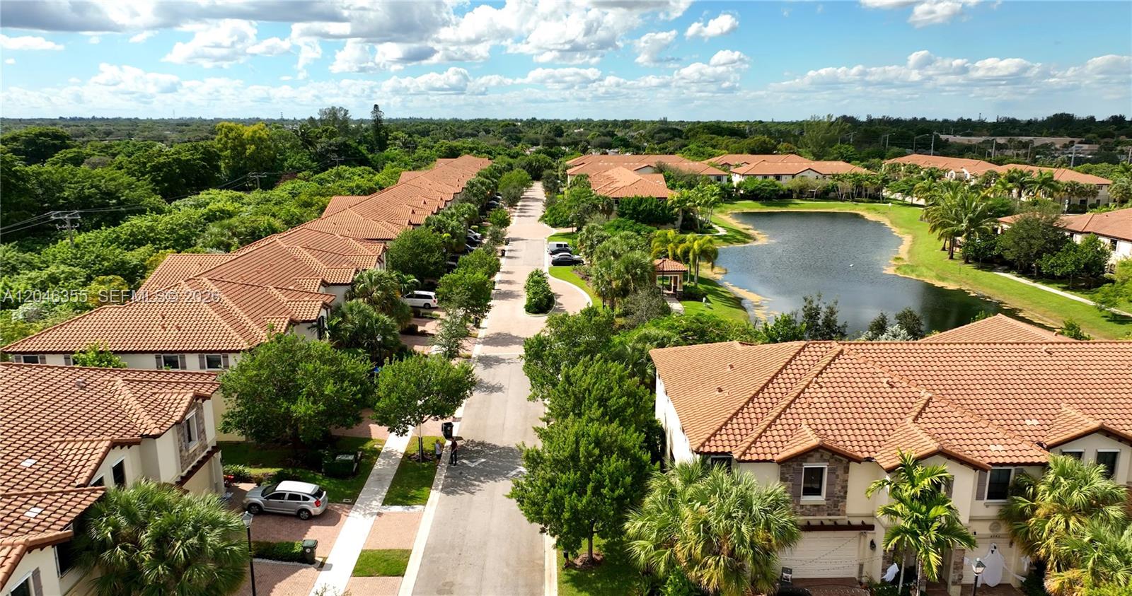 An aerial view shows a residential street lined with townhouses, trees, and a small lake — 3962 Devenshire Ct, Coconut Creek FL 33073, COCONUT CREEK, FL