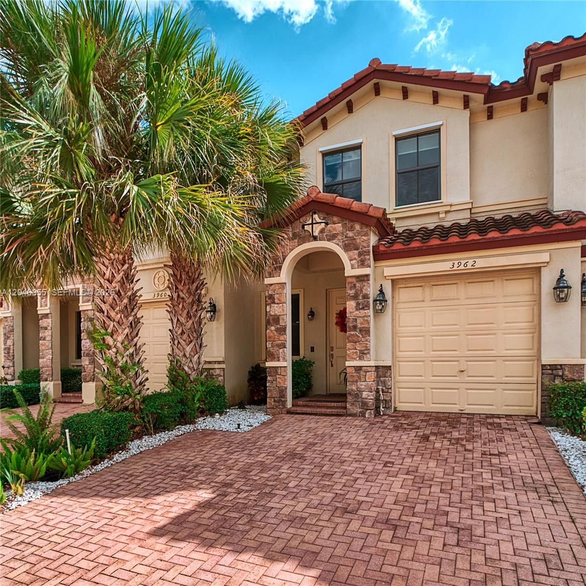 A two-story townhouse with a stone-accented entryway, a brick driveway, and a palm tree — 3962 Devenshire Ct, Coconut Creek FL 33073, COCONUT CREEK, FL