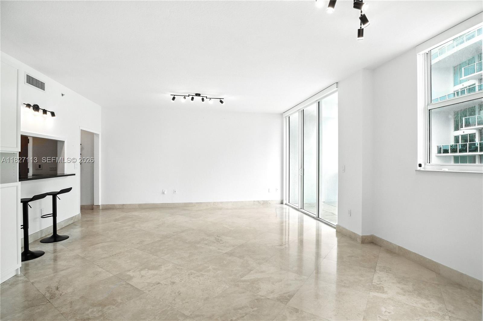 An empty living room features white walls, tile flooring, a breakfast bar, and sliding glass doors — 31 SE 5th St # 4021, Miami FL 33131, MIAMI, FL