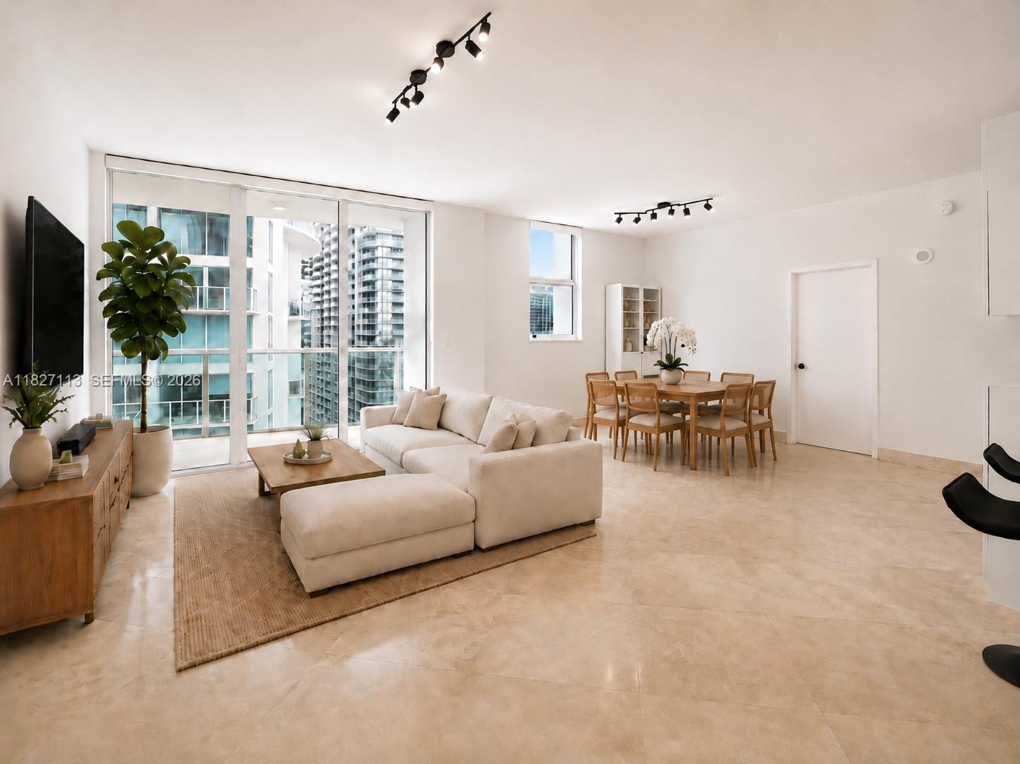 A modern living and dining area features white walls, tile floors, and floor-to-ceiling windows — 31 SE 5th St # 4021, Miami FL 33131, MIAMI, FL