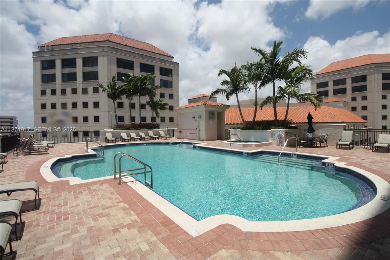 An outdoor swimming pool with lounge chairs on a brick deck between two large buildings — 888 S Douglas Rd # 1213, Coral Gables FL 33134, CORAL GABLES, FL