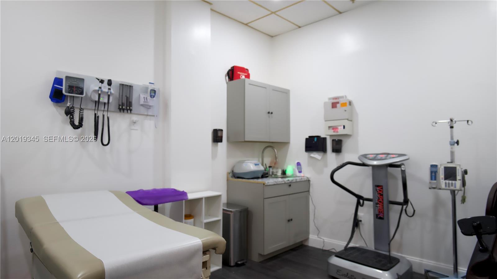 This medical examination room features a treatment table, a vibration platform, and wall-mounted diagnostic equipment — 8684 Griffin Rd, Cooper City FL 33328, COOPER CITY, FL