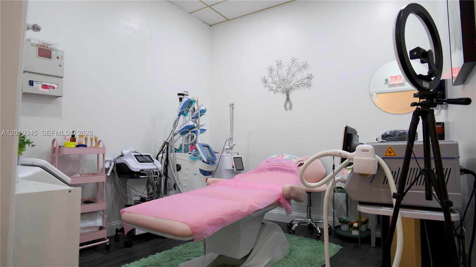 A medical aesthetic treatment room features a procedure chair, various equipment, and a ring light — 8684 Griffin Rd, Cooper City FL 33328, COOPER CITY, FL