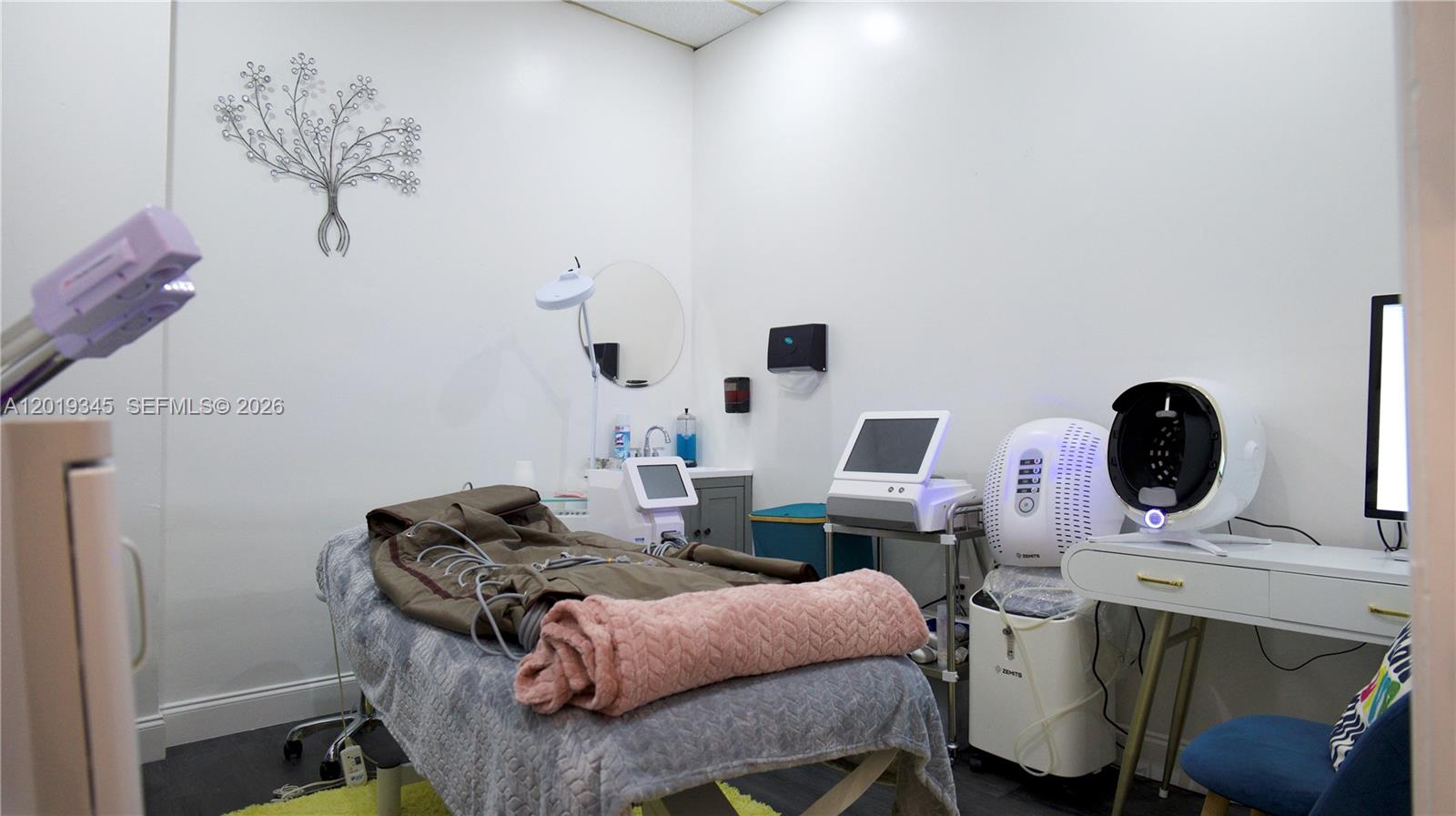 A treatment room features a massage table, various aesthetic medical devices, and white walls — 8684 Griffin Rd, Cooper City FL 33328, COOPER CITY, FL