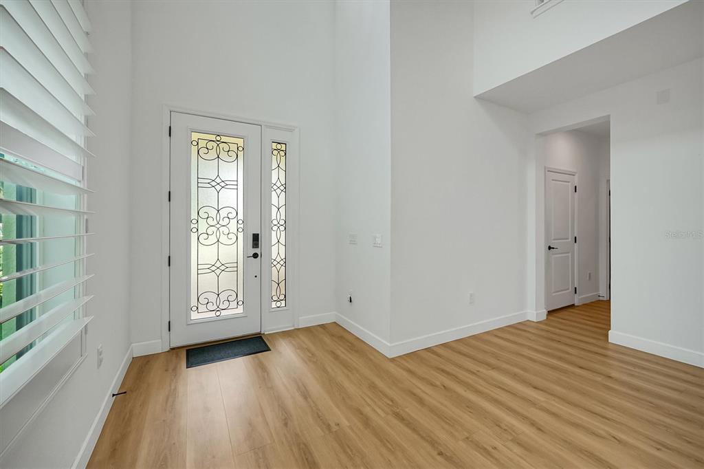 An entryway with light wood-look flooring, white walls, a high ceiling, and a decorative glass door — 1316 BLUE STEM LANE, WINTER PARK, FL