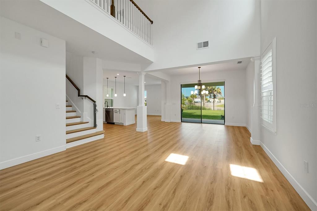 A bright, open-concept living area features light wood flooring, a staircase, and a sliding glass door — 1316 BLUE STEM LANE, WINTER PARK, FL