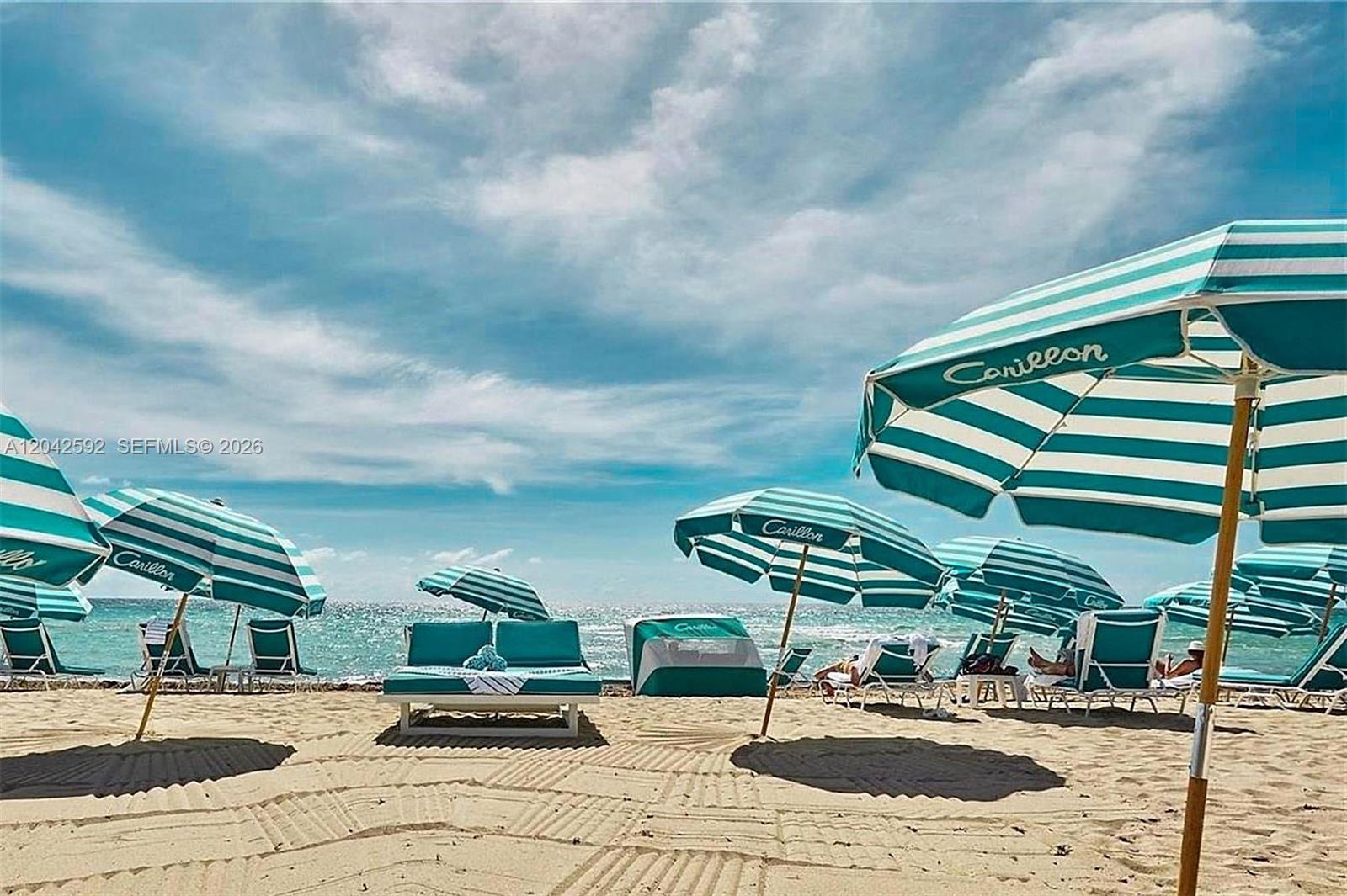 A sandy beach features several teal and white striped umbrellas and lounge chairs — 6801 Collins Ave # 1101, Miami Beach FL 33141, MIAMI BEACH, FL