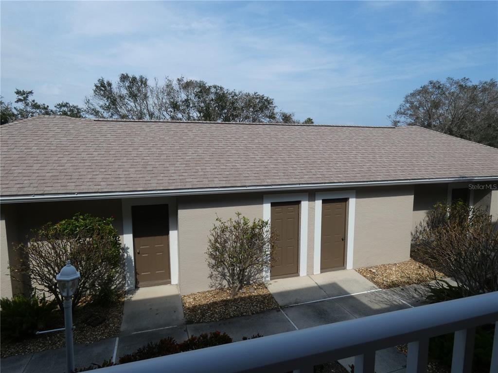 An exterior view of a single-story building with three brown doors and a shingled roof — 9641 CASTLE POINT DRIVE UNIT 1225, SARASOTA, FL