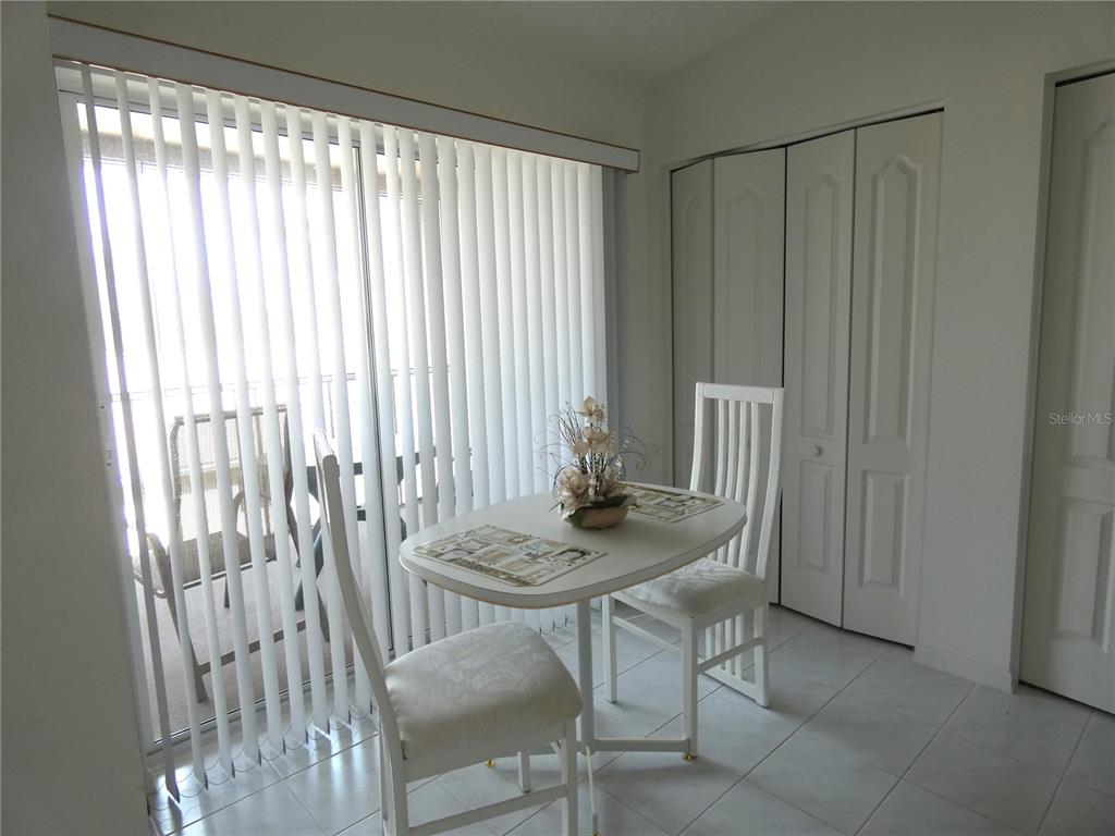 A dining area features a small white table, two chairs, tile flooring, and vertical blinds — 9641 CASTLE POINT DRIVE UNIT 1225, SARASOTA, FL
