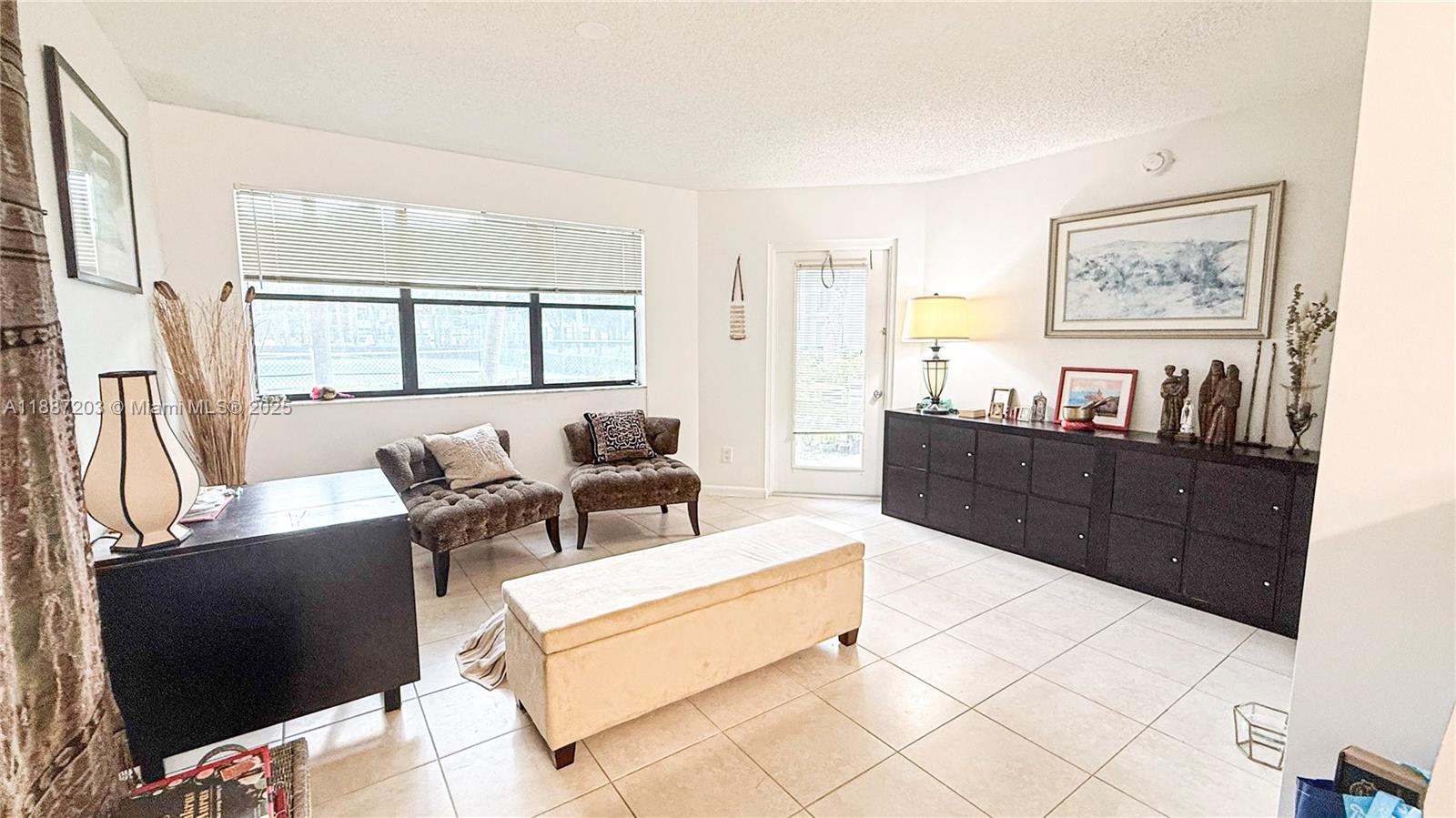 A living room features tile flooring, a large window, a dark sideboard, and two chairs — 540 S Park Rd # 9, Hollywood FL 33021, HOLLYWOOD, FL