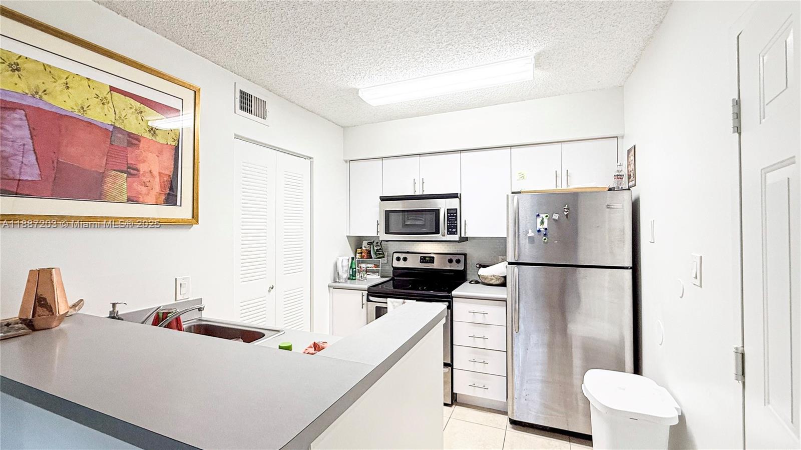 A kitchen features white cabinetry, stainless steel appliances, and a gray countertop peninsula — 540 S Park Rd # 9, Hollywood FL 33021, HOLLYWOOD, FL