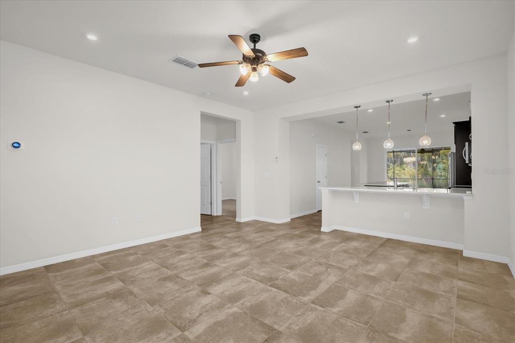 A living room with tile flooring, a ceiling fan, and an open kitchen with pendants — 2444 VARENNA LOOP, KISSIMMEE, FL