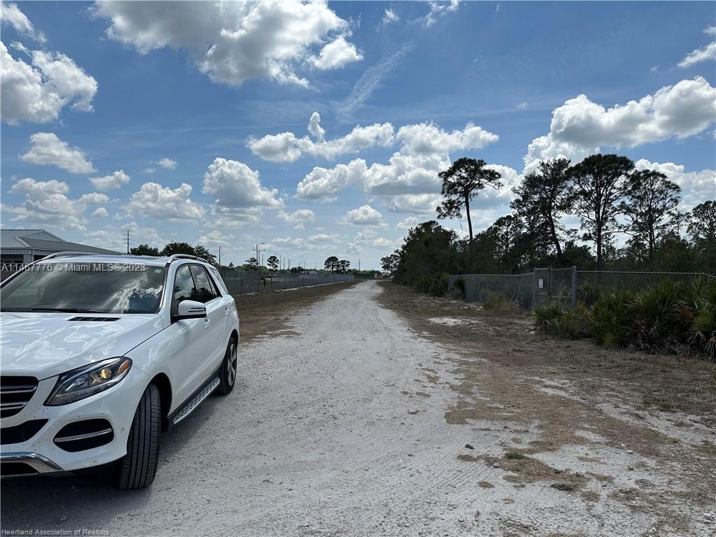A white SUV is parked on a dirt road next to a chain-link fence — 5128 Coruna Avenue, Sebring FL 33872, SEBRING, FL