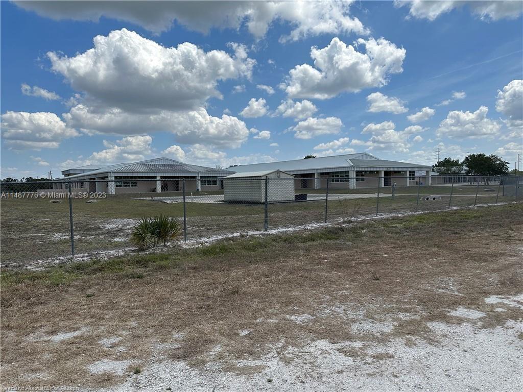 A chain-link fence encloses a grassy lot with two single-story buildings and a shed — 5128 Coruna Avenue, Sebring FL 33872, SEBRING, FL