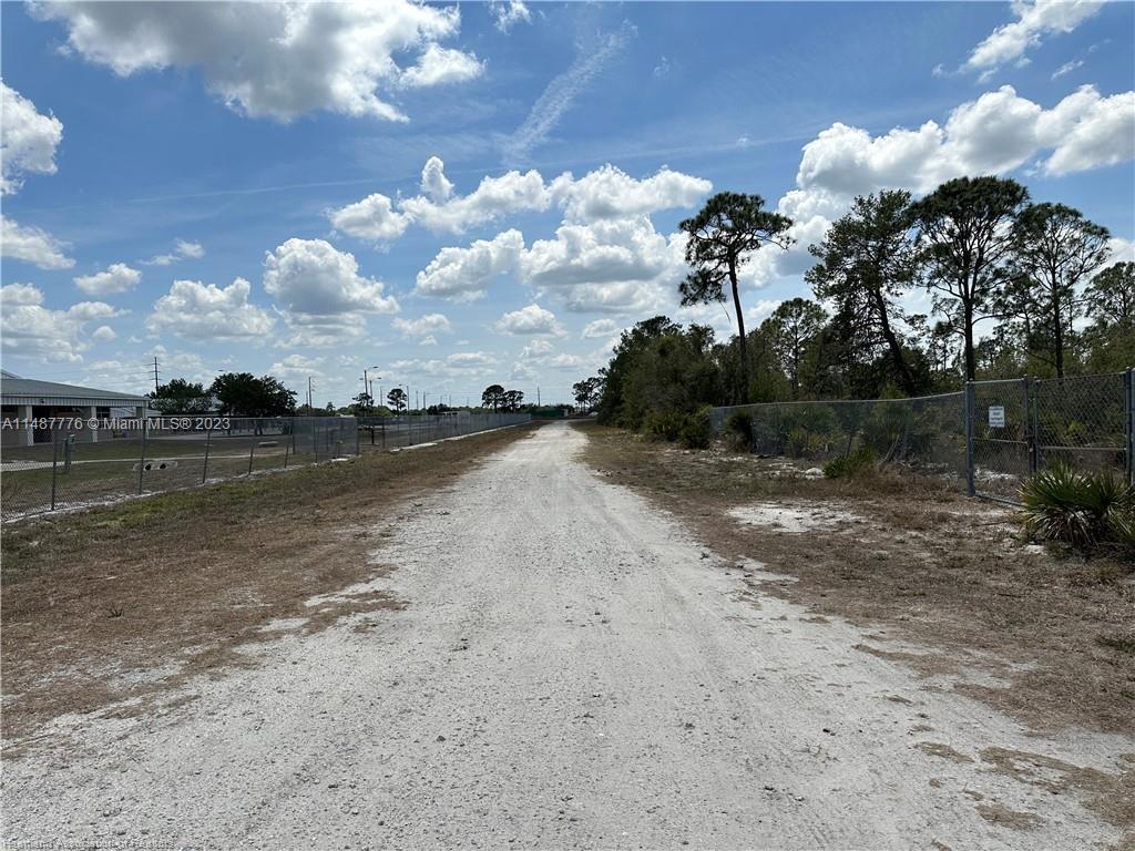 A dirt path runs between a chain-link fence and a wooded area under a cloudy sky — 5128 Coruna Avenue, Sebring FL 33872, SEBRING, FL