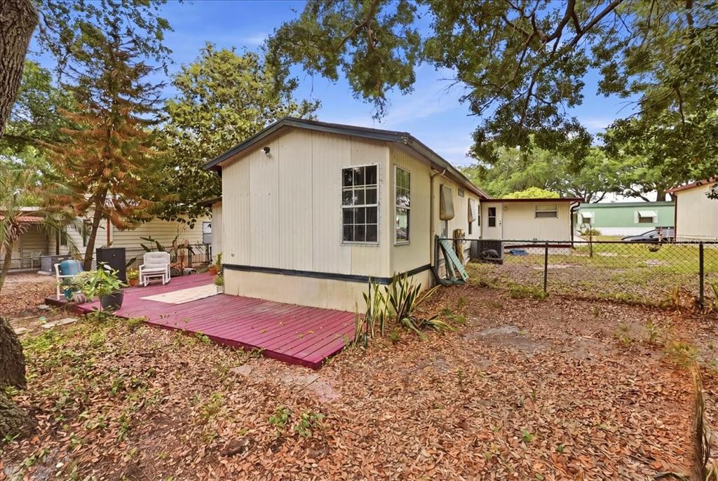 A mobile home features a red wooden deck and a chain-link fence in the yard — 1908 REGINA DRIVE, LAKE ALFRED, FL