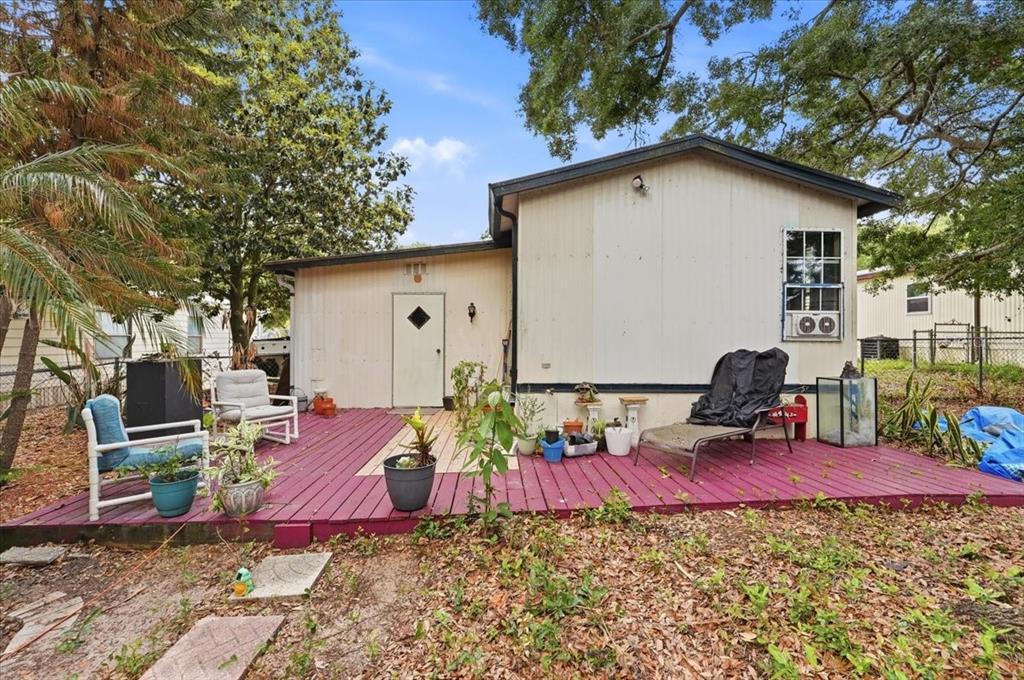 A mobile home exterior features a red wooden deck with outdoor furniture and potted plants — 1908 REGINA DRIVE, LAKE ALFRED, FL