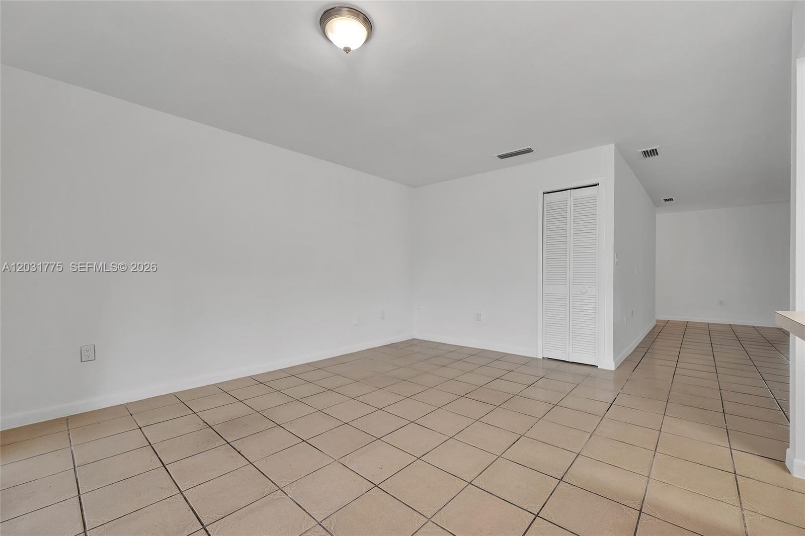 An empty room features white walls, a light fixture, and beige square floor tiles — 23 NW 109th Ave, Miami FL 33172, MIAMI, FL