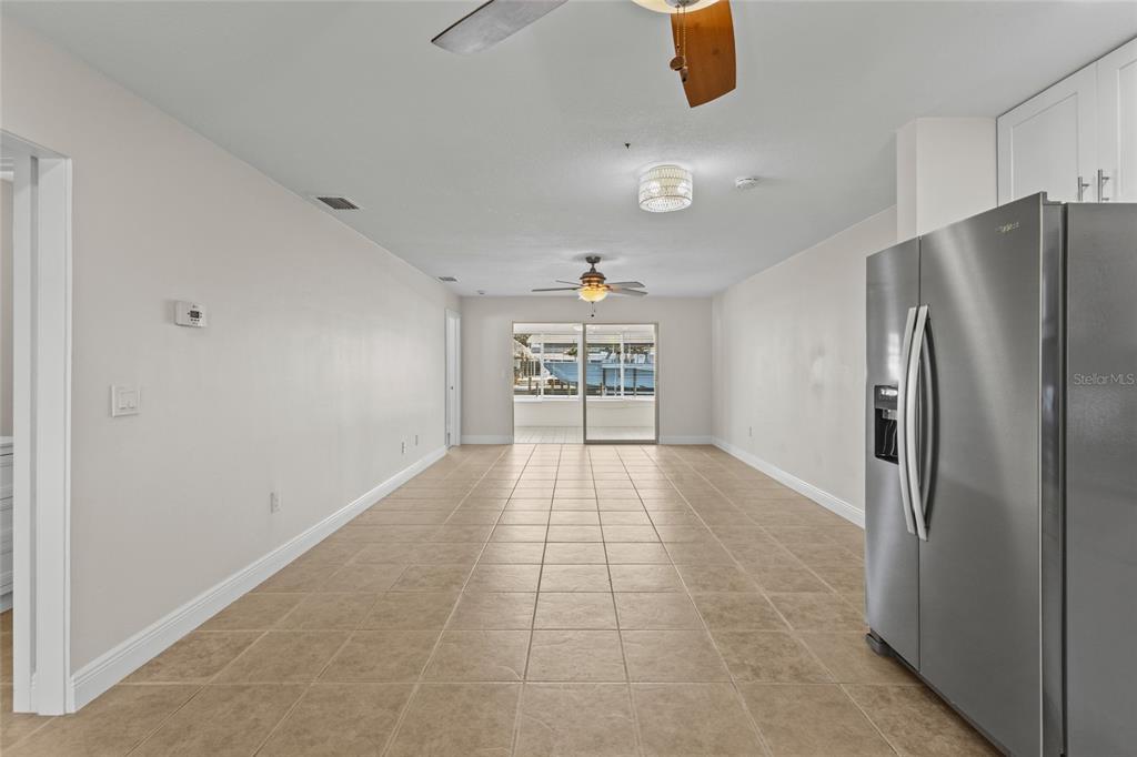 A long, tiled room features a stainless steel refrigerator and a sliding glass door — 9821 HERNANDO COURT, BRADENTON, FL