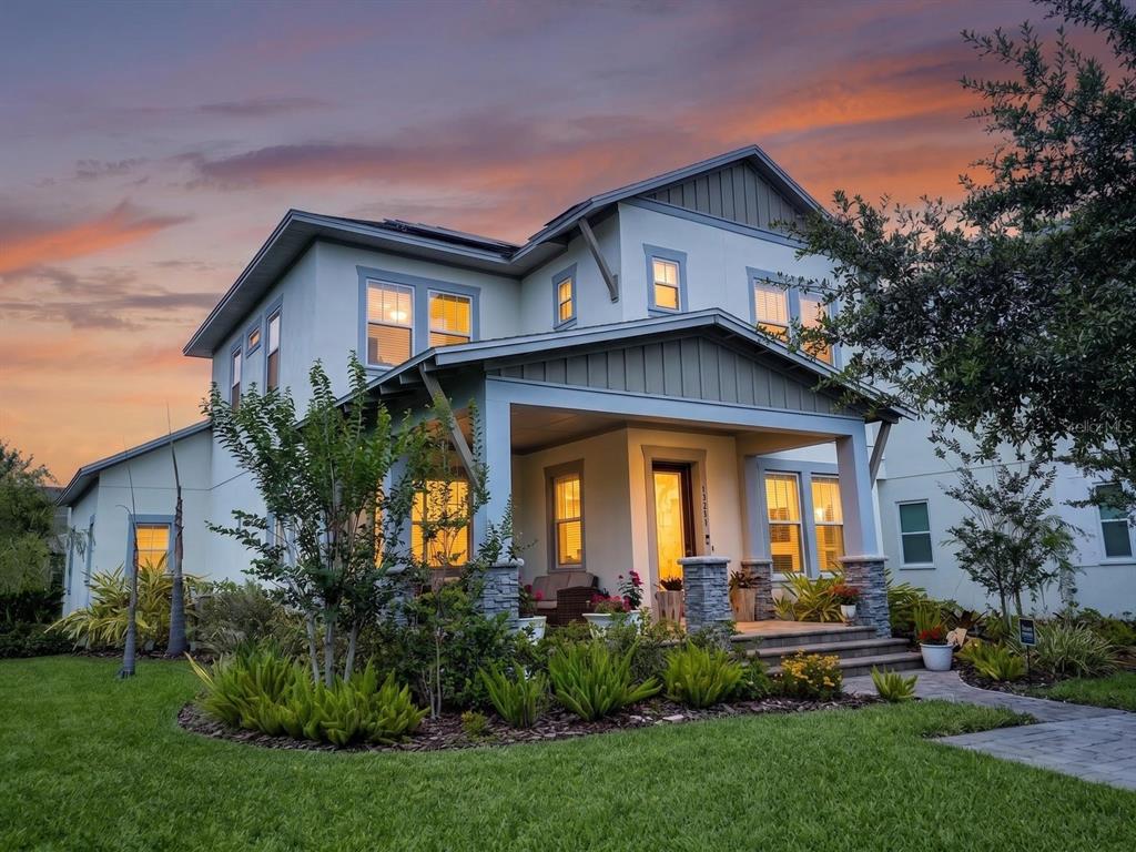 A two-story house with a covered front porch, stone pillars, and a landscaped front yard — 13201 GRANGER AVENUE, ORLANDO, FL