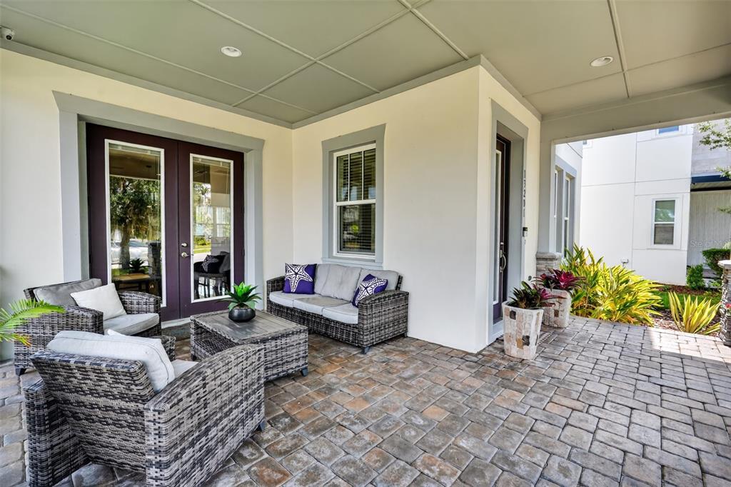 A covered patio features wicker furniture, a stone-paver floor, and a set of French doors — 13201 GRANGER AVENUE, ORLANDO, FL
