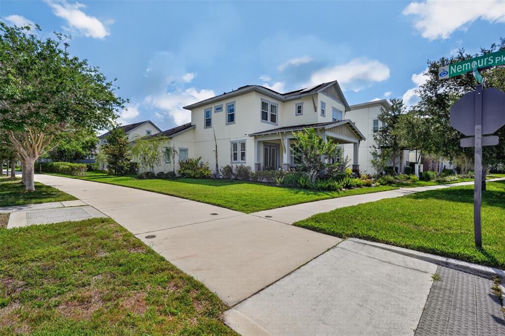 A two-story house with a light-colored exterior sits on a corner lot with sidewalks — 13201 GRANGER AVENUE, ORLANDO, FL