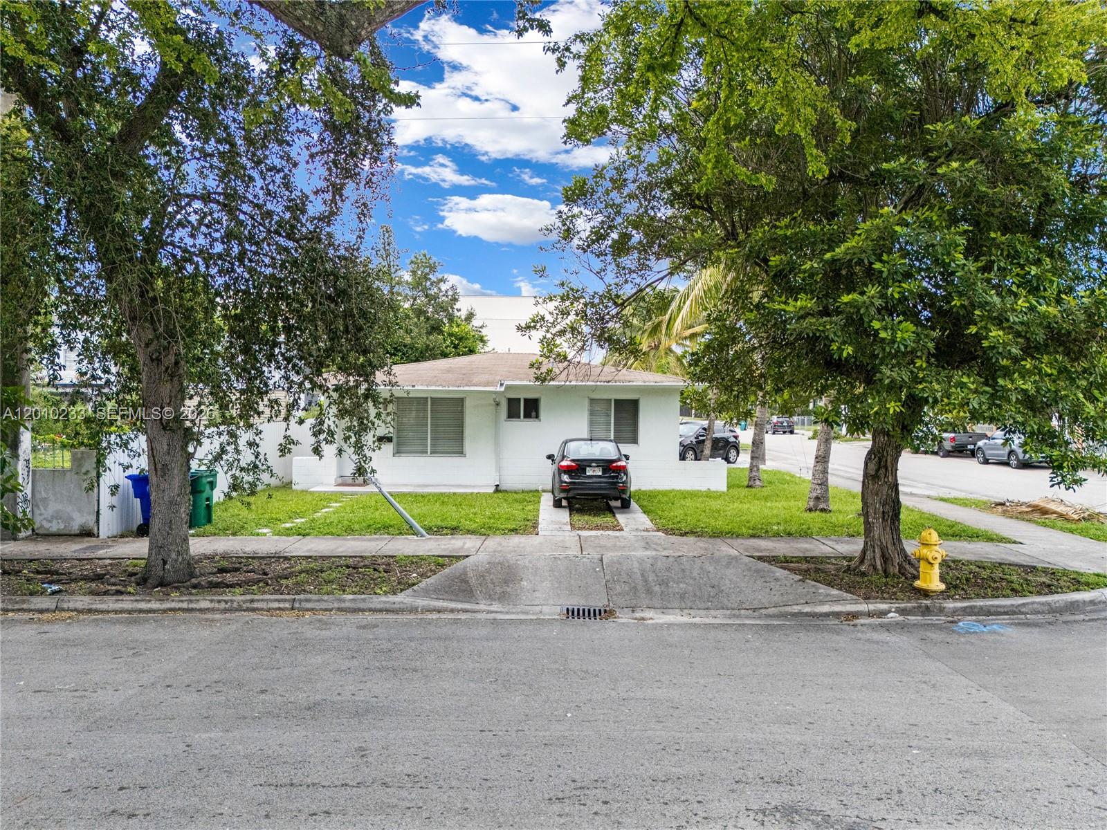 A white single-story house with a front lawn, driveway, and two large trees — 301 NW 34th St, Miami FL 33127, MIAMI, FL