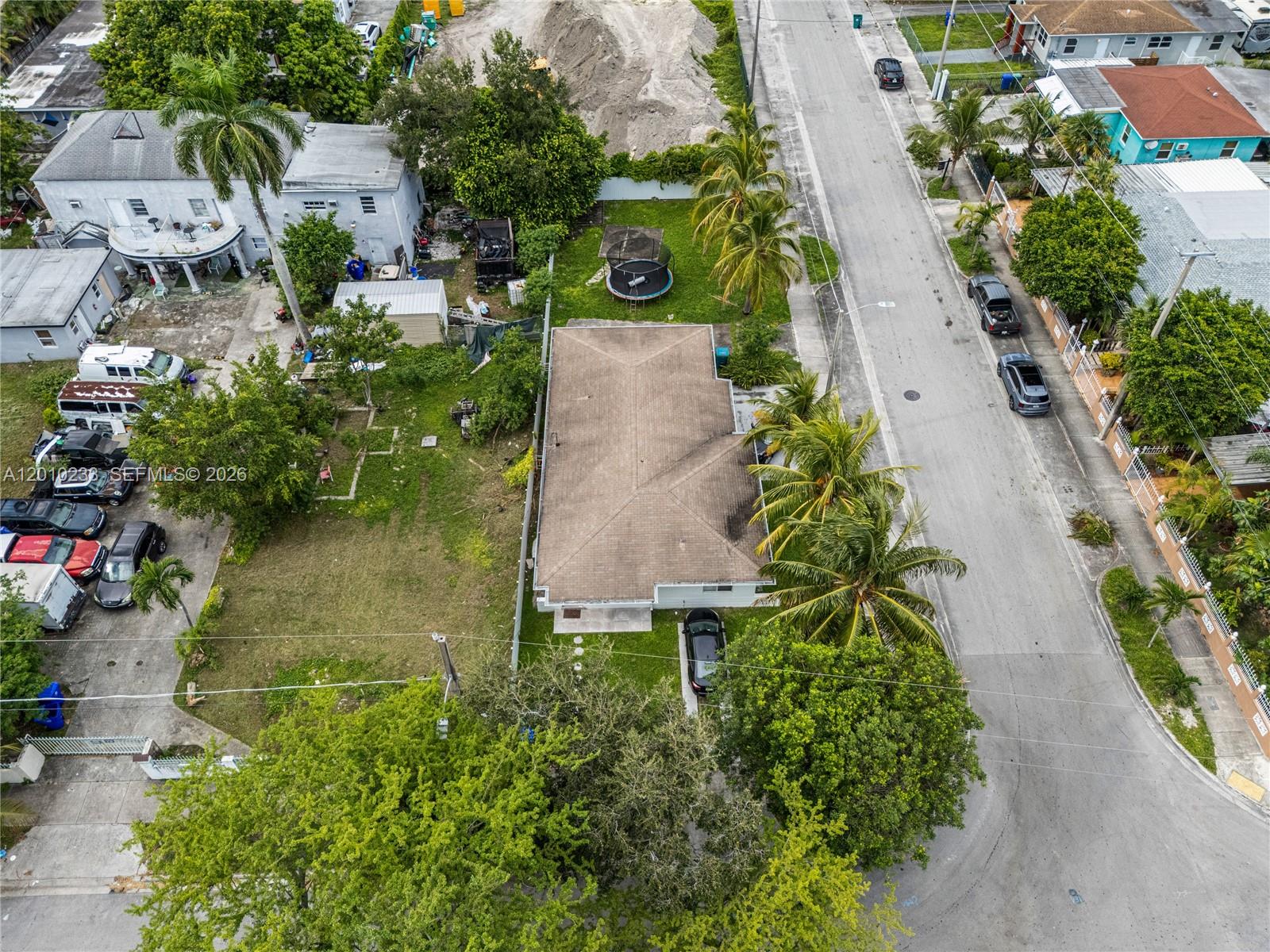 An aerial view shows a single-story house with a brown roof, palm trees, and driveway — 301 NW 34th St, Miami FL 33127, MIAMI, FL