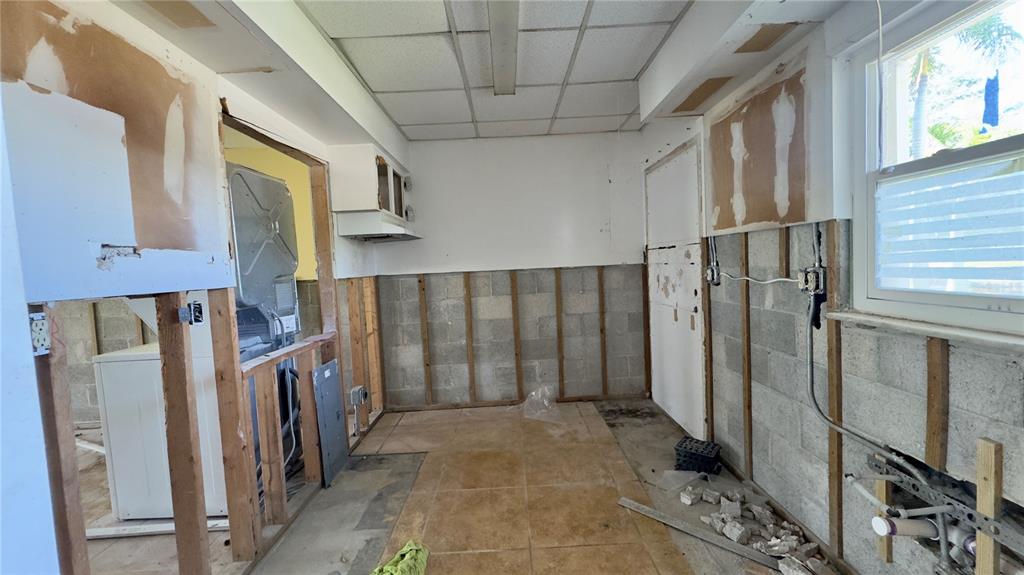 An unfinished kitchen with exposed concrete block walls, wood framing, and tile flooring — 3136 HARBOR BOULEVARD UNIT 2A, PORT CHARLOTTE, FL