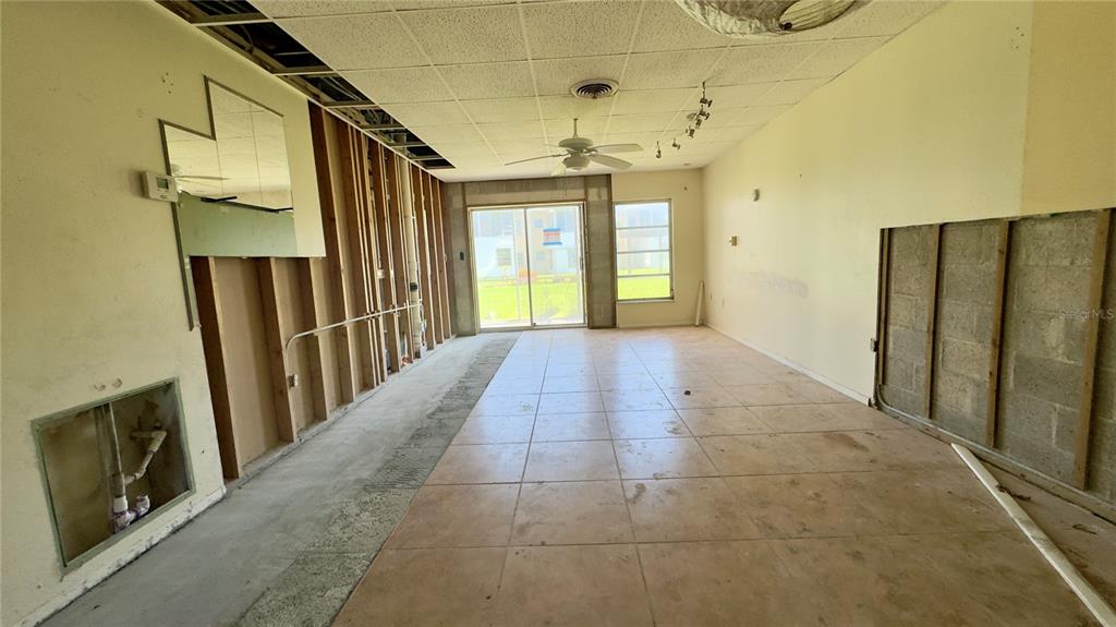An unfinished living room features exposed wall studs, tiled flooring, and a ceiling fan — 3136 HARBOR BOULEVARD UNIT 2A, PORT CHARLOTTE, FL