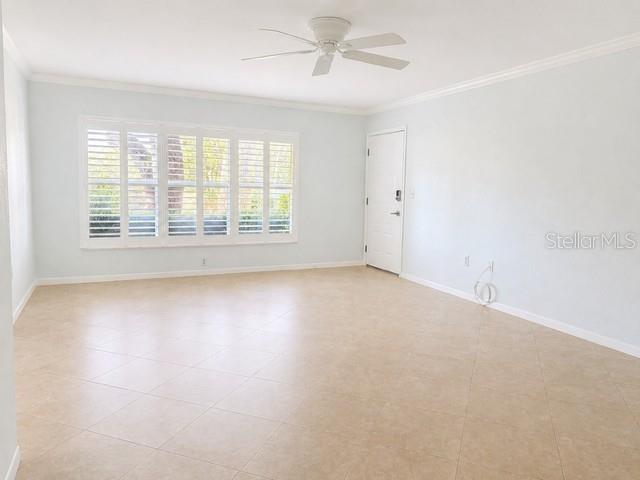 An empty room features light-colored tile flooring, white walls, plantation shutters, and a ceiling fan — 2106 GULF VIEW BOULEVARD UNIT 2106, DUNEDIN, FL