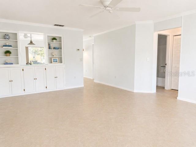 A bright living area features white built-in cabinets, shelving, and a ceiling fan — 2106 GULF VIEW BOULEVARD UNIT 2106, DUNEDIN, FL