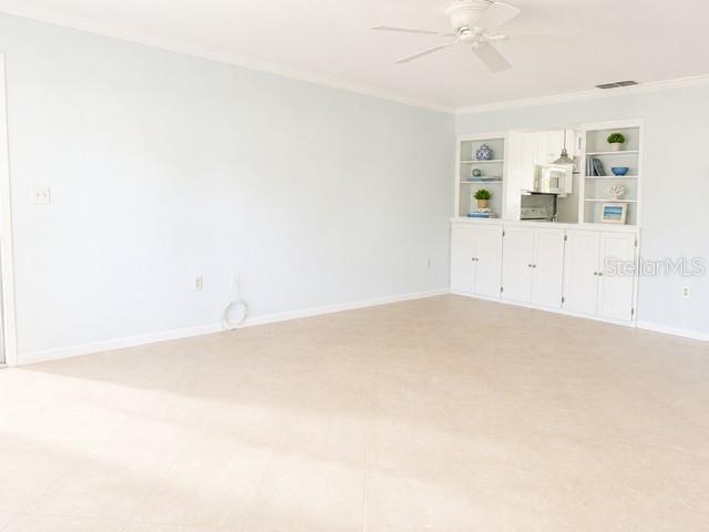 A spacious room features light blue walls, tile flooring, a ceiling fan, and built-in cabinetry — 2106 GULF VIEW BOULEVARD UNIT 2106, DUNEDIN, FL