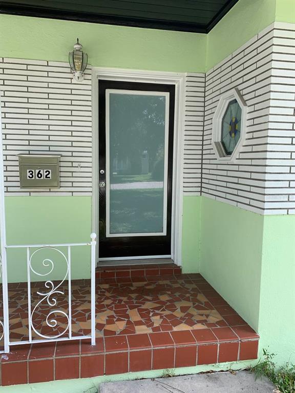 A front porch with a tiled floor, a black door, and a decorative hexagonal window — 362 FOSTER LANE, BELLEAIR, FL