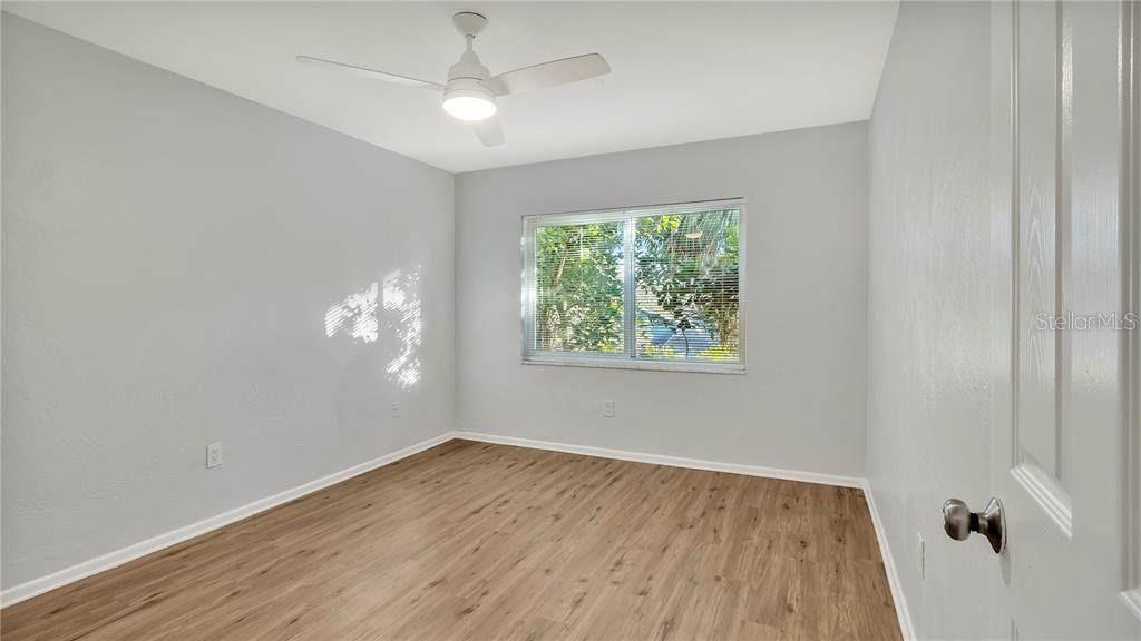 An empty bedroom features light gray walls, wood-look flooring, a ceiling fan, and a window — 5900 22ND AVENUE N, ST PETERSBURG, FL